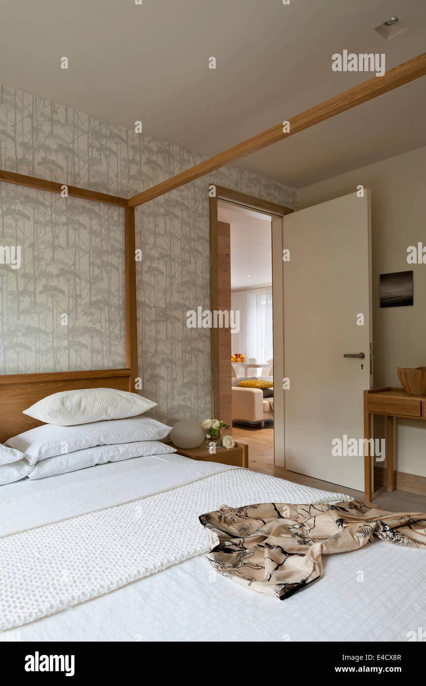 Mirrored storage wall in bedroom with a Hana oak four poster bed by Habitat and Putkinotko wallpaper by Marimekko Stock Photo