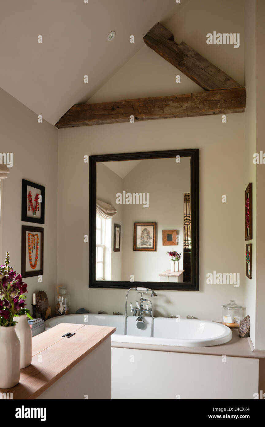 Large black framed mirror in bathroom with oval ended bath from Aston Matthews Stock Photo