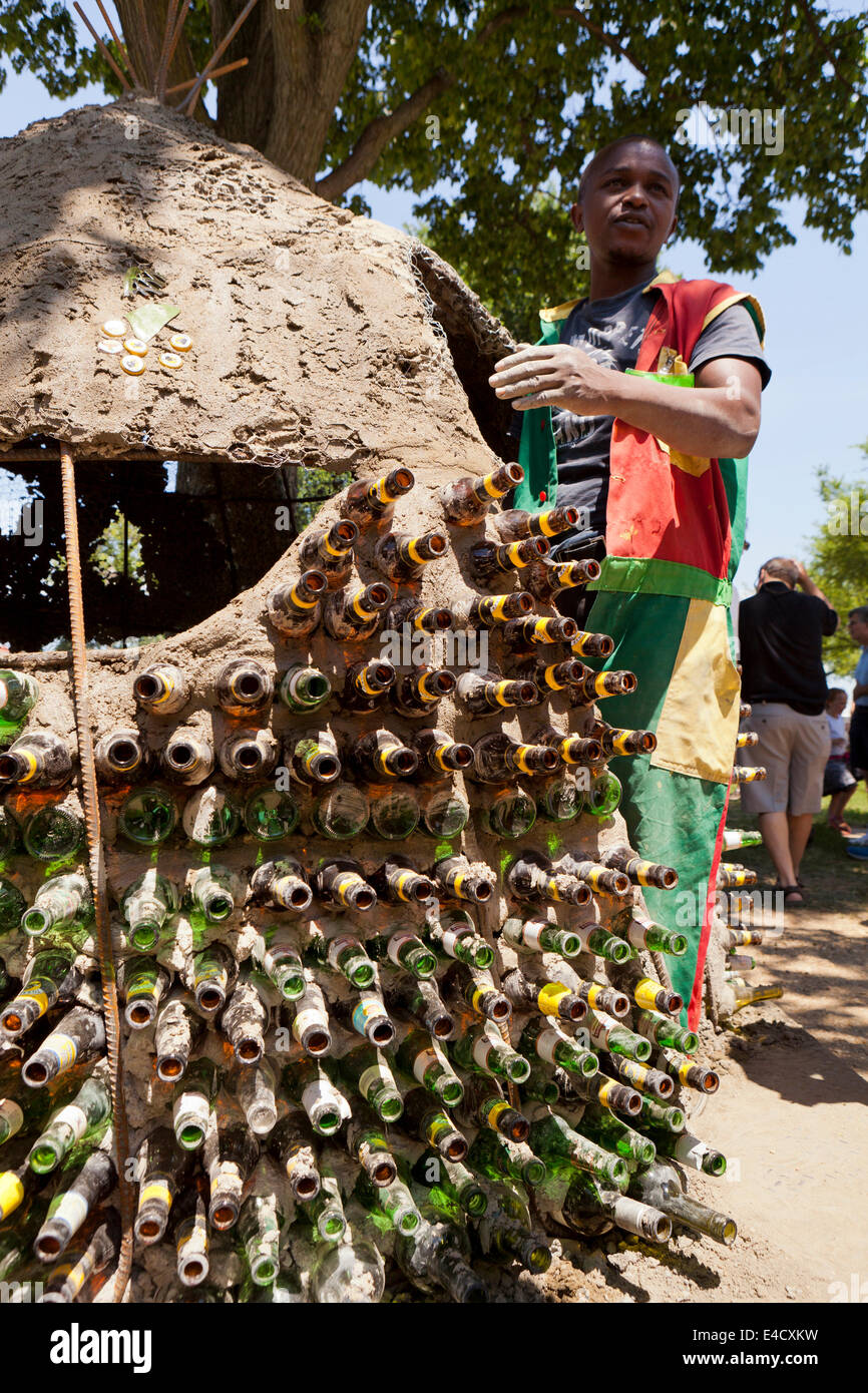 Kenyan man building a mud hut using glass bottles and other recycled materials Stock Photo