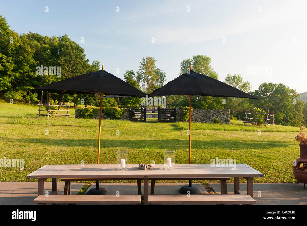 Black parasols on terrace with table and bench and garden views Stock Photo