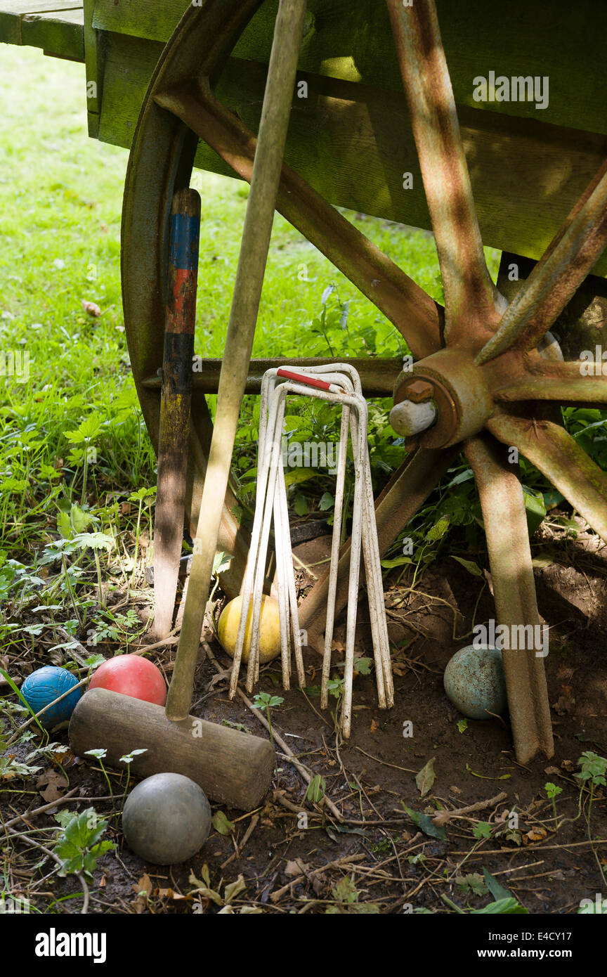 A croquet set leaning up against an old iron wheel Stock Photo