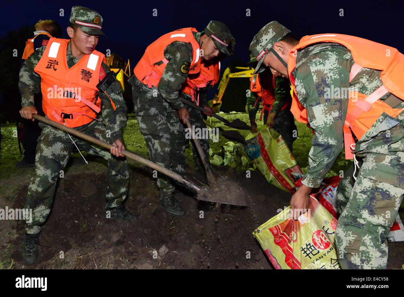Baicheng, China's Jilin Province. 8th July, 2014. Soldiers of Jilin Armed Police Corps fill sandbags to close up breaches in Xijiatun of Lingxia Town in Baicheng, northeast China's Jilin Province, July 8, 2014. A total of about 700 flood-stranded residents have been relocated. Credit:  Yuan Jun/Xinhua/Alamy Live News Stock Photo