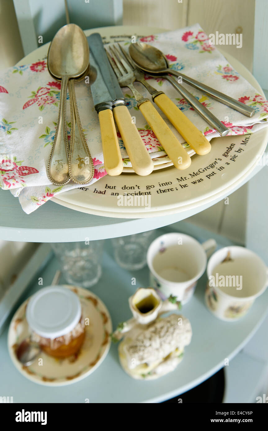 Bone handled cutlery on Cath Kidstone style print napkins on tiered shelf with crockery Stock Photo