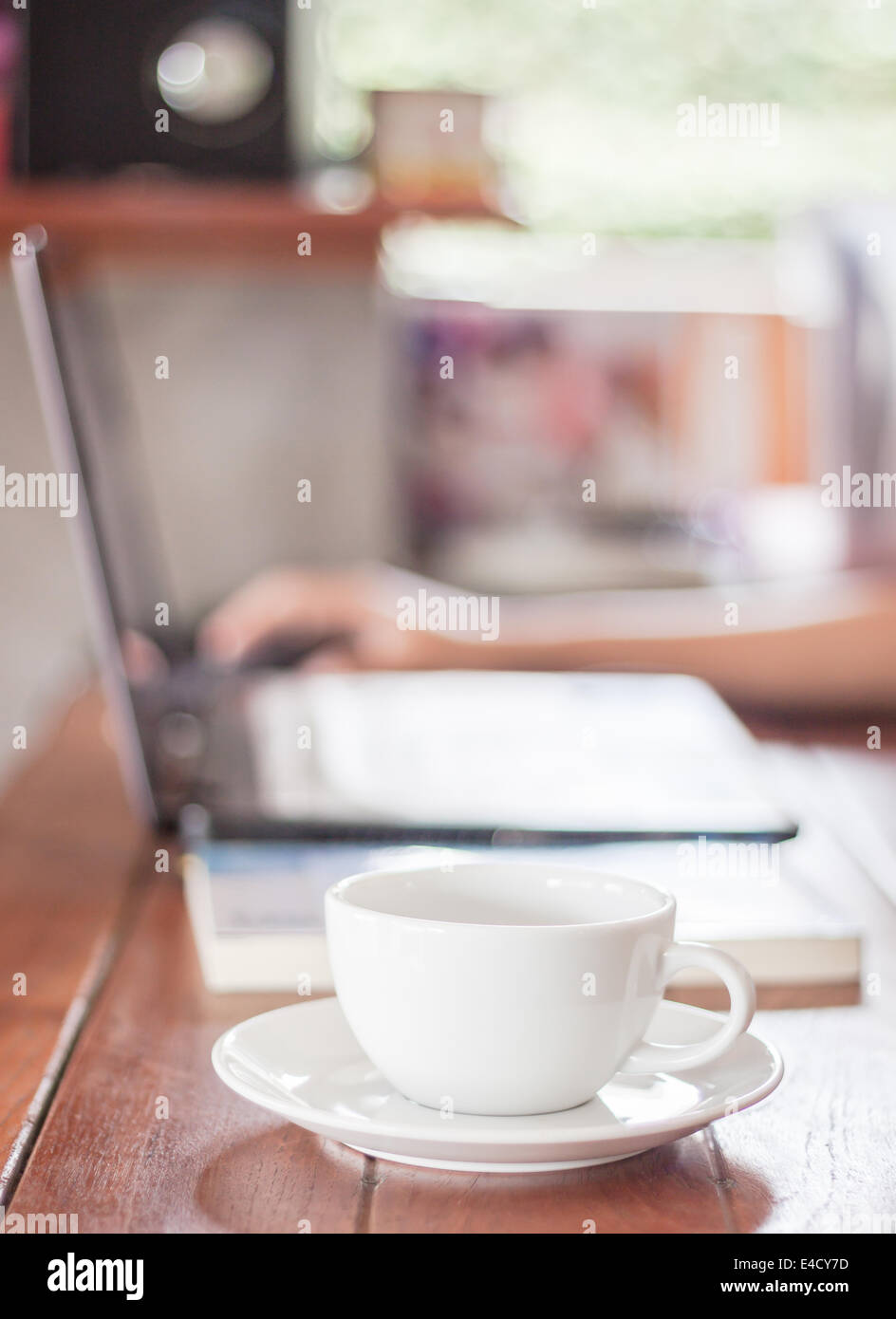 Woman using laptop with a white cup of coffee, stock photo Stock Photo