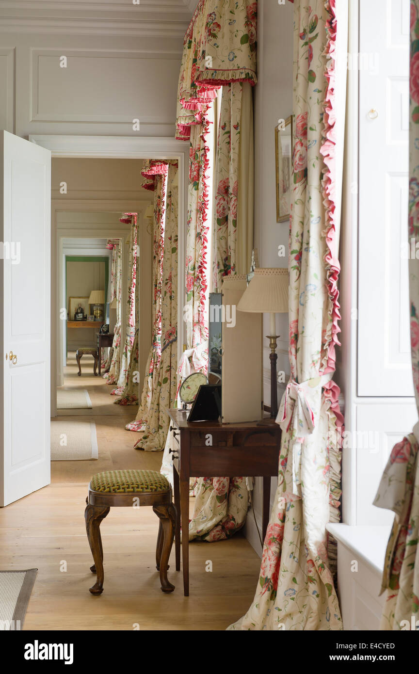 An 18th century dressing table with embroidered stool in room with floor-length chintz curtains Stock Photo