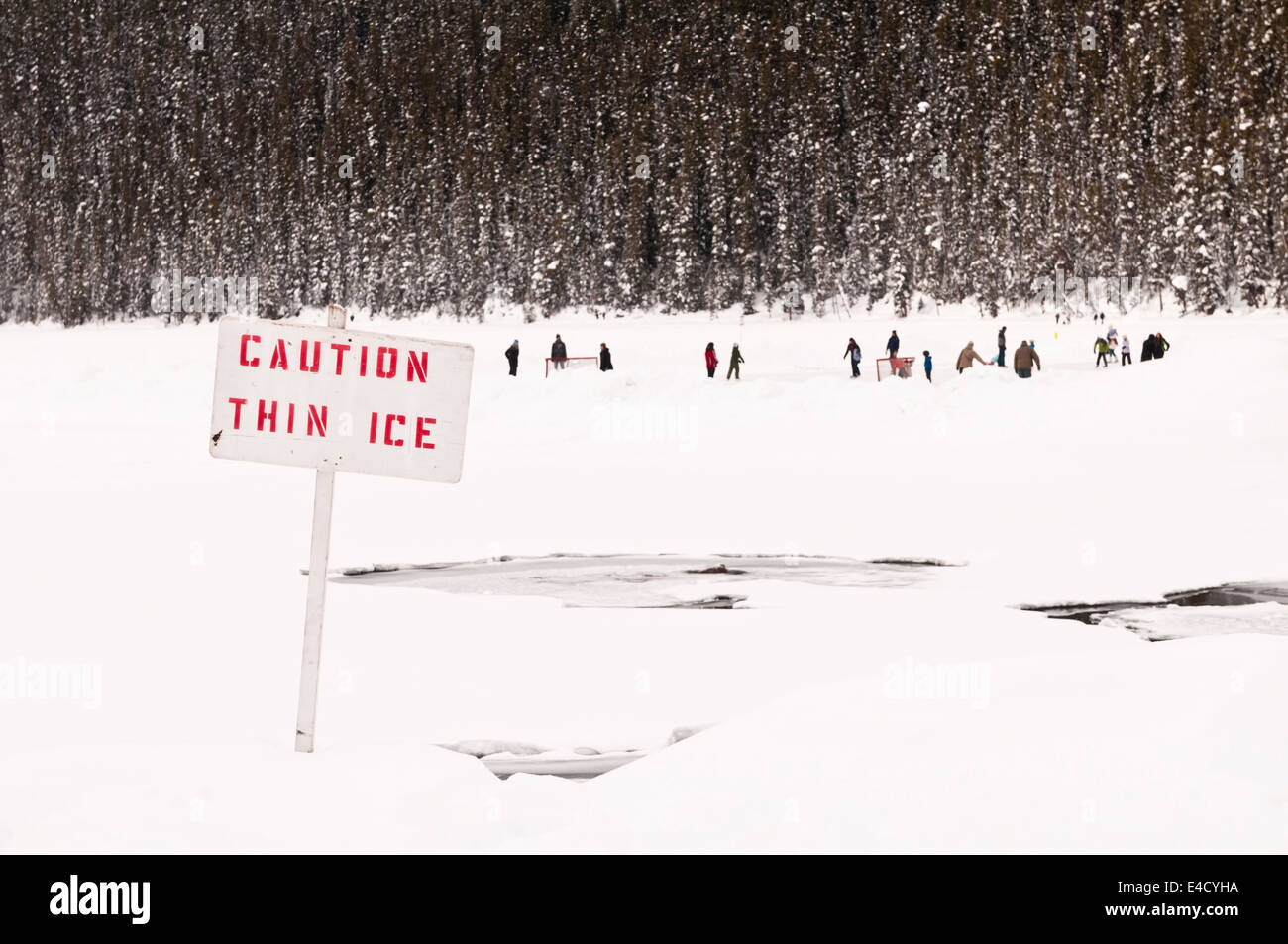 Caution Thin Ice, sign, with people in the background, Lake Louise, Banff National Park, Alberta, Canada Stock Photo