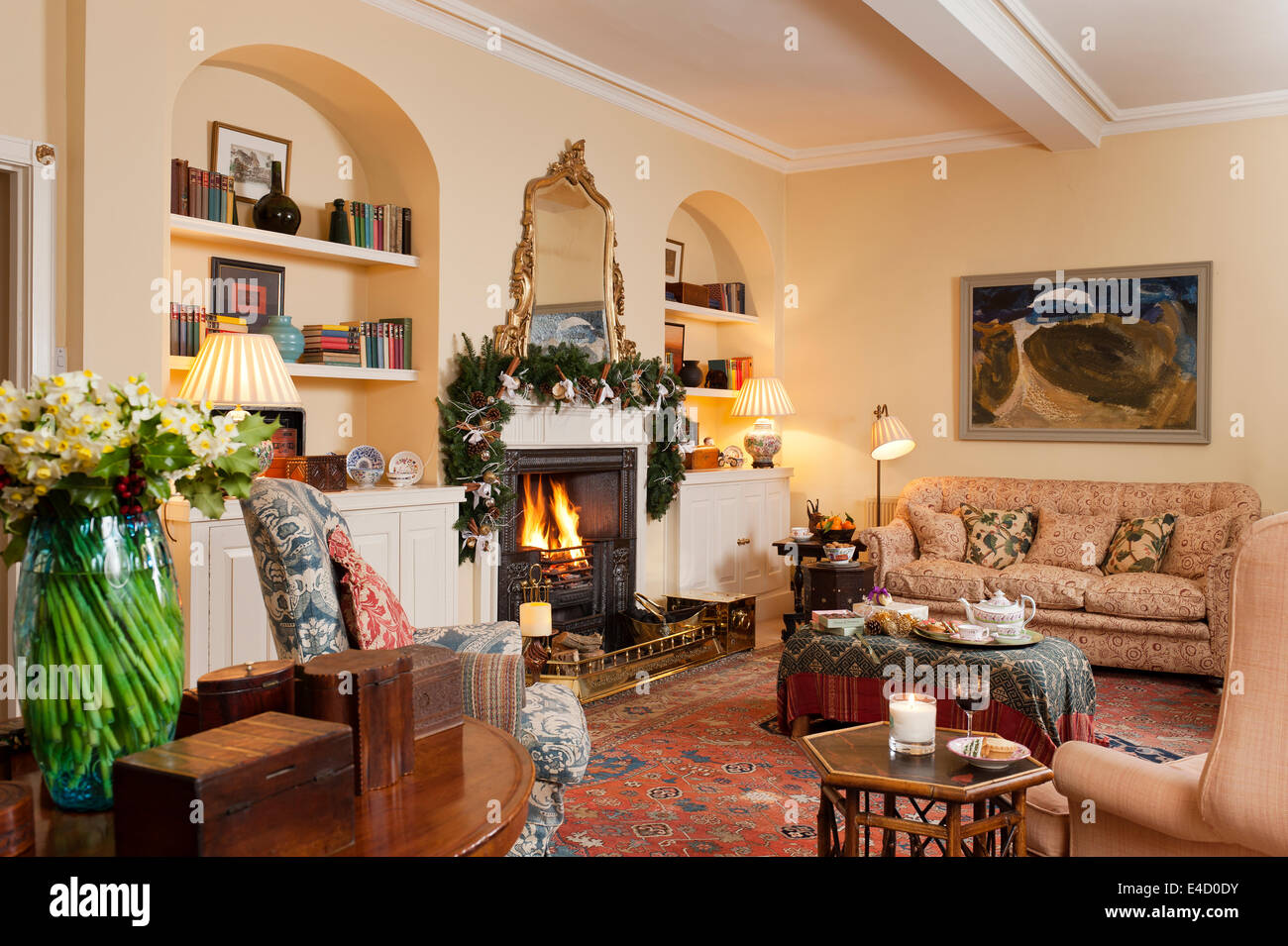 Cosy sitting room with fireplace and assorted antique furniture. The sofa is early 19th century and upholstered in Bennison line Stock Photo