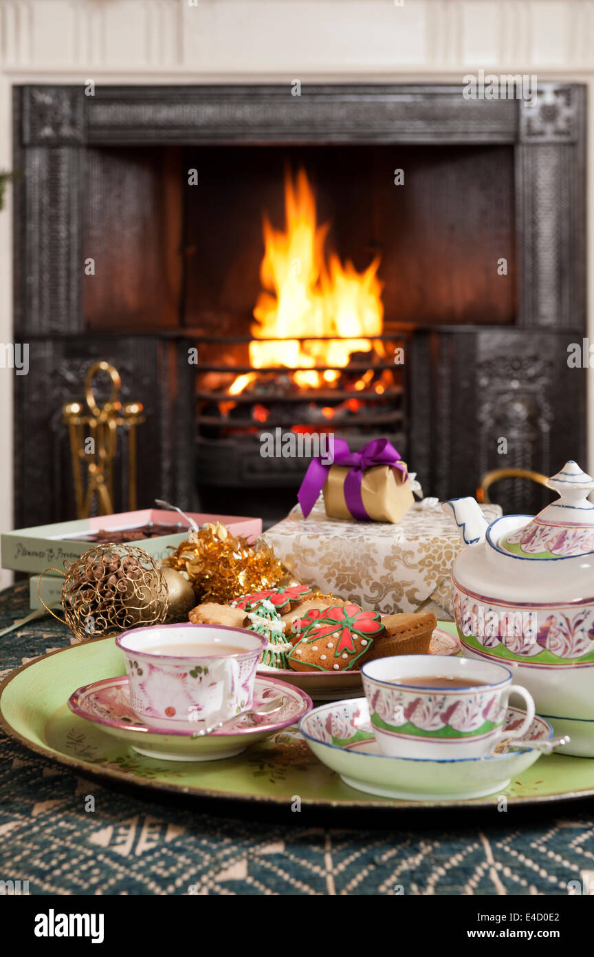 19C hand-painted lustre porcelain tea set tray with christmas biscuits in front of fireplace Stock Photo