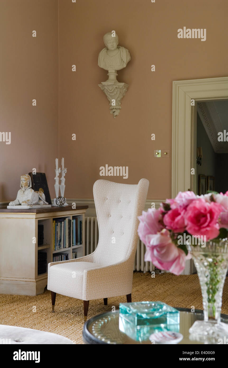 Wing chair upholstered in Veere Grenney Temple fabric in grand salon. A plaster bust sits on a ledge on the wall Stock Photo