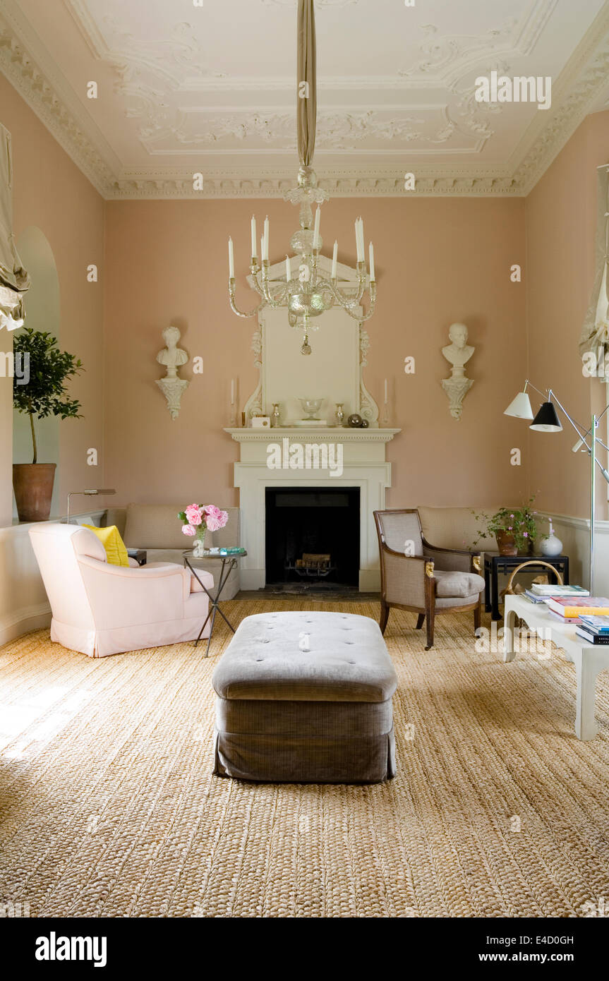 An ottoman covered in Decor de Paris velvet in grand salon with chandelier and elaborate stucco over-mantel Stock Photo