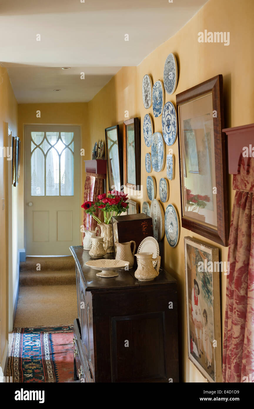 Porcelain drain plates mounted on wall of corridor with old wooden chest Stock Photo