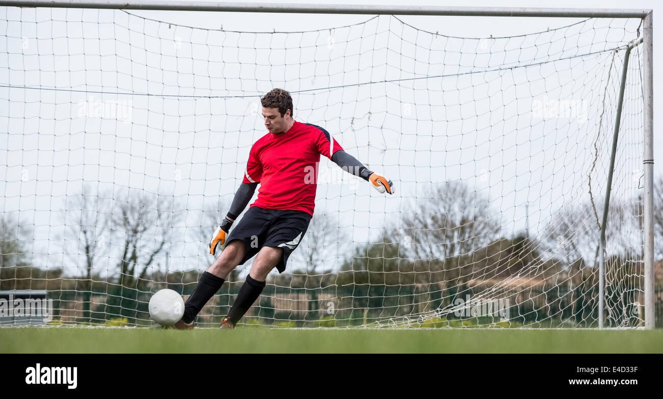 Goalkeeper Rushing Out Goalkeeper in red kicking ball away from goal Stock Photo - Alamy