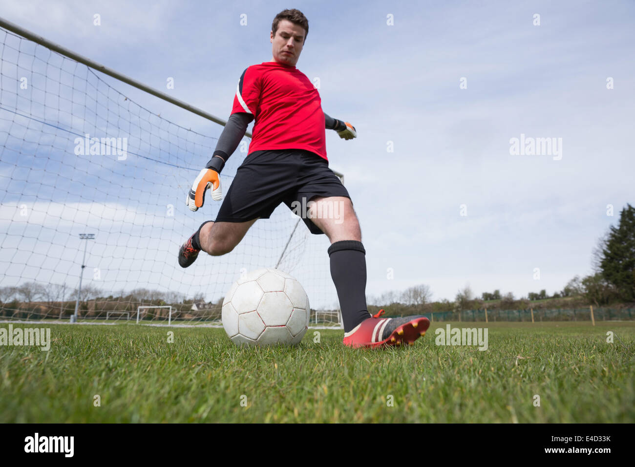 Goalkeeper Rushing Out Goalkeeper in red kicking ball away from goal Stock Photo - Alamy