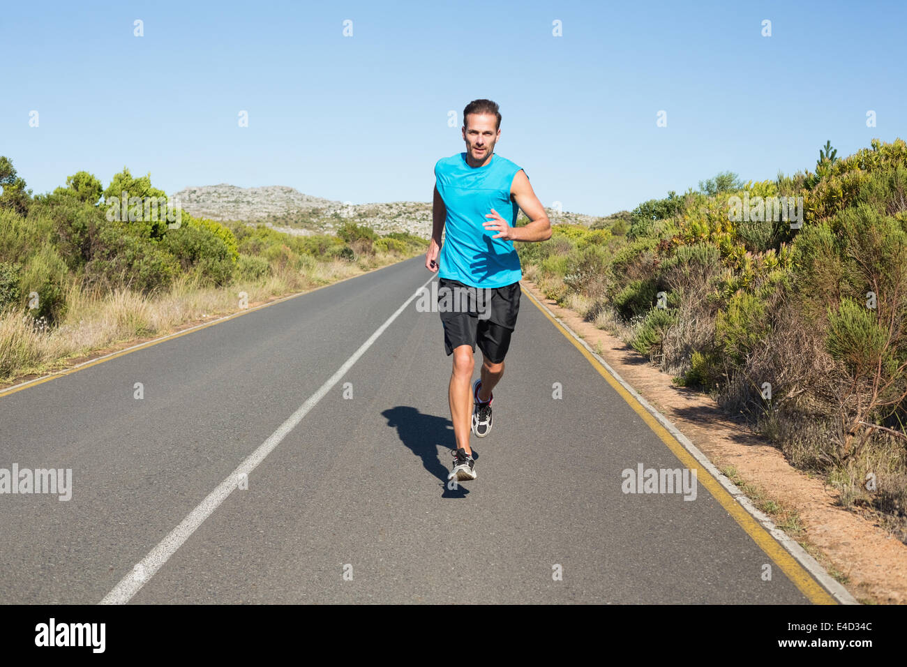 Fit man jogging on the open road Stock Photo