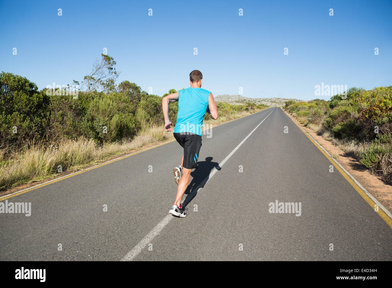Fit man jogging on the open road Stock Photo