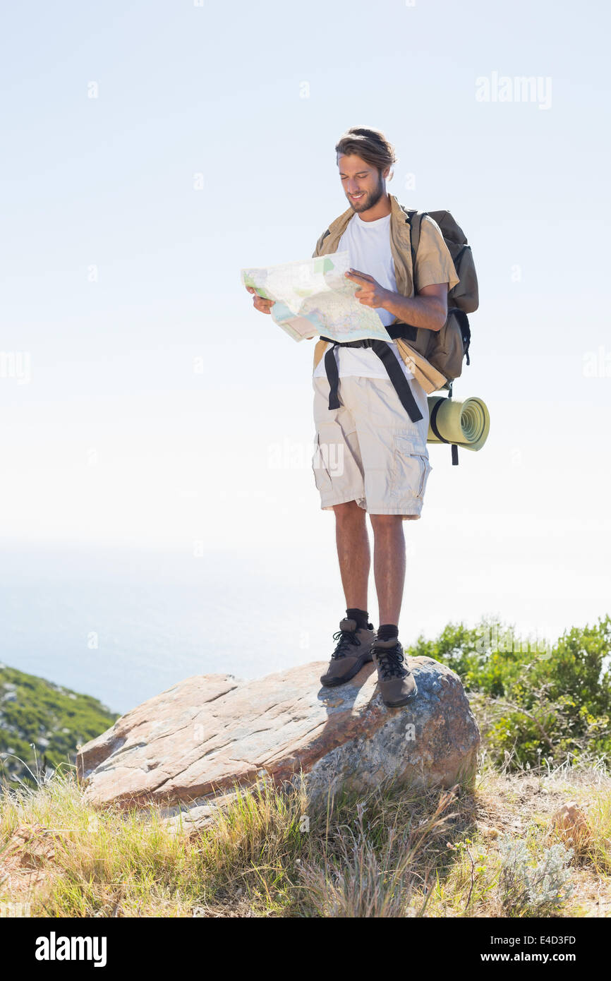 Handsome hiker holding map at mountain summit Stock Photo