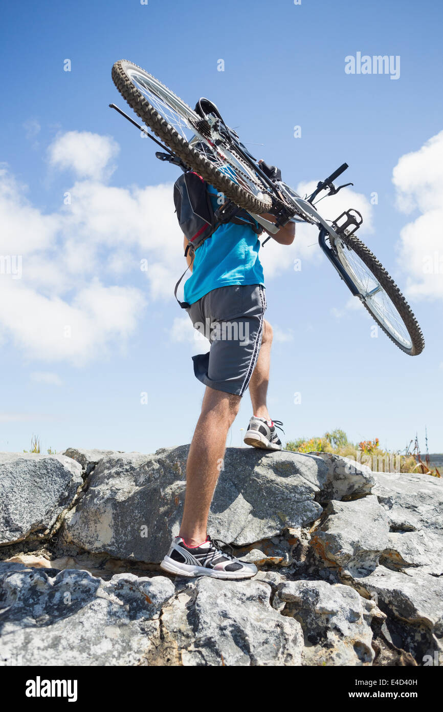 Fit man walking up rocky terrain holding mountain bike Stock Photo Alamy