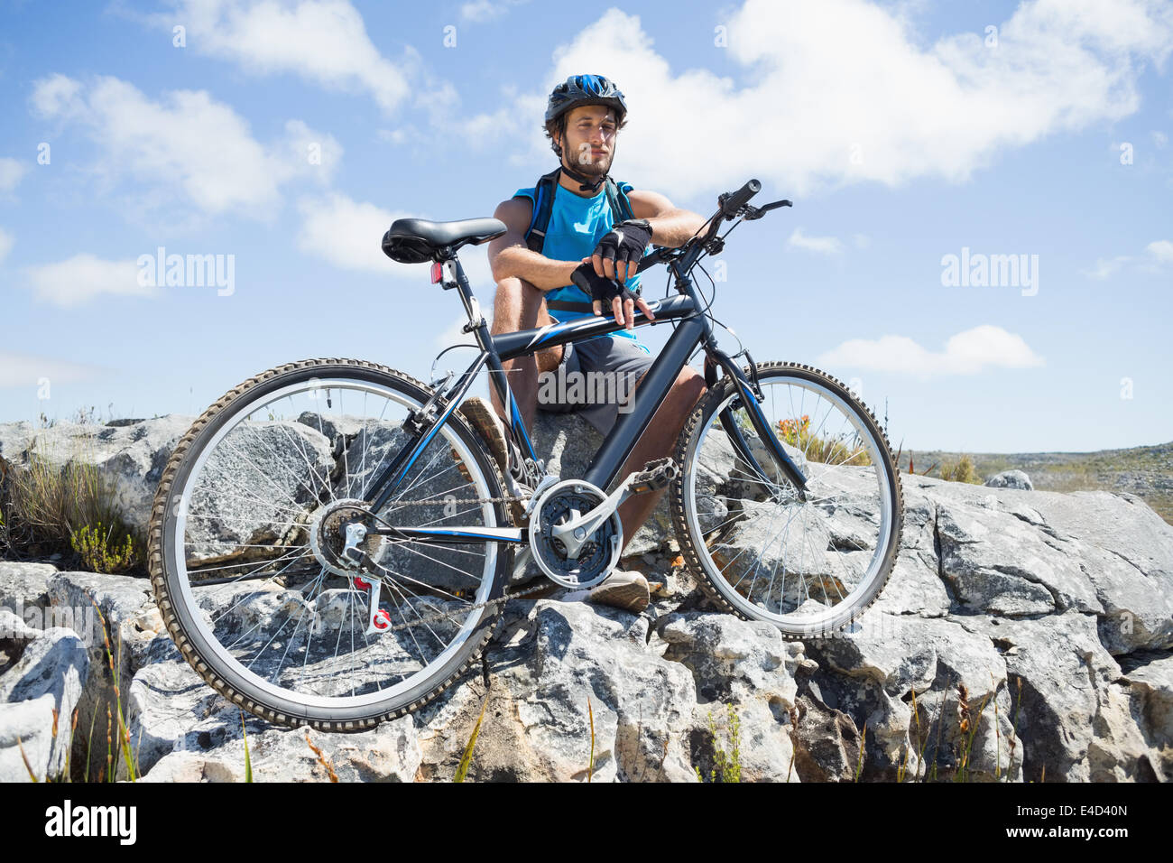 Fit cyclist taking a break on rocky peak Stock Photo