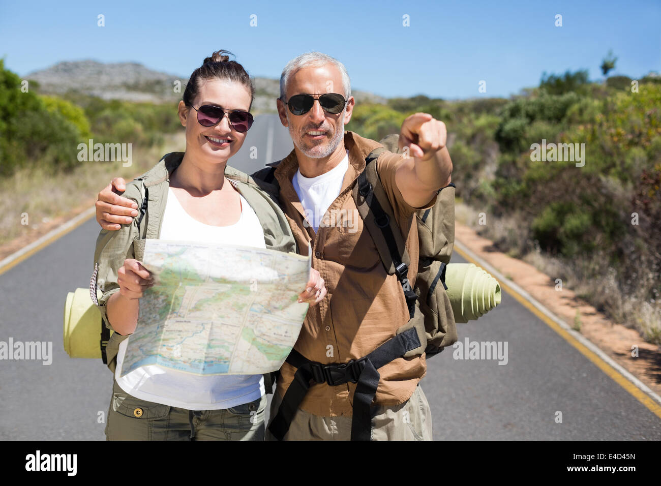 Hiking couple looking at map on the road Stock Photo - Alamy