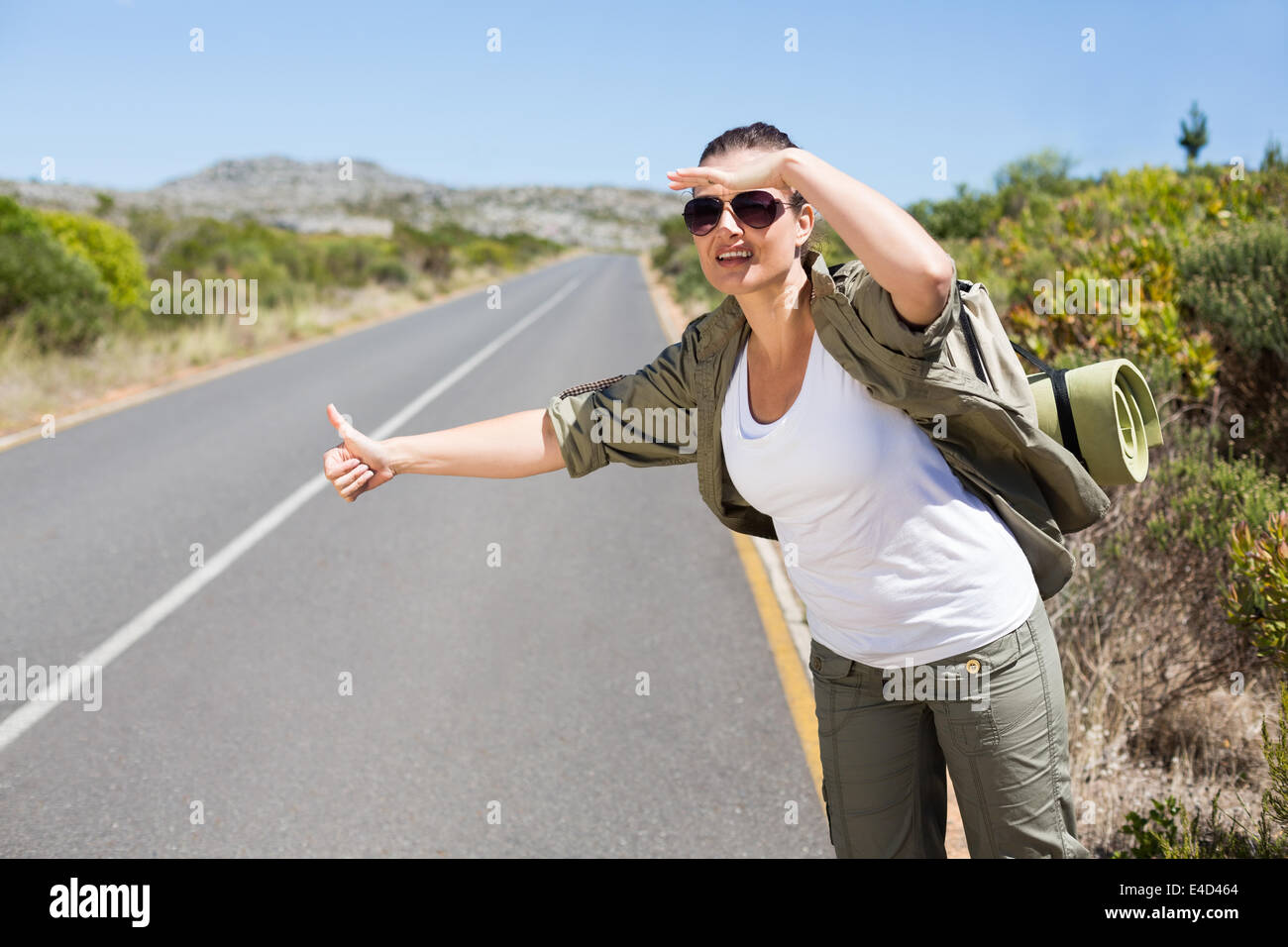 Pretty hitchhiker sticking thumb out on the road Stock Photo