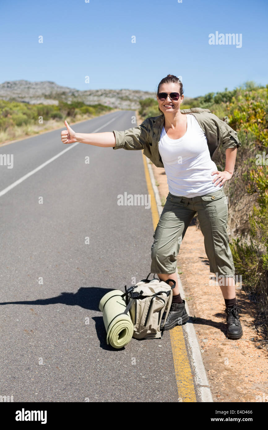 Pretty hitchhiker sticking thumb out on the road Stock Photo