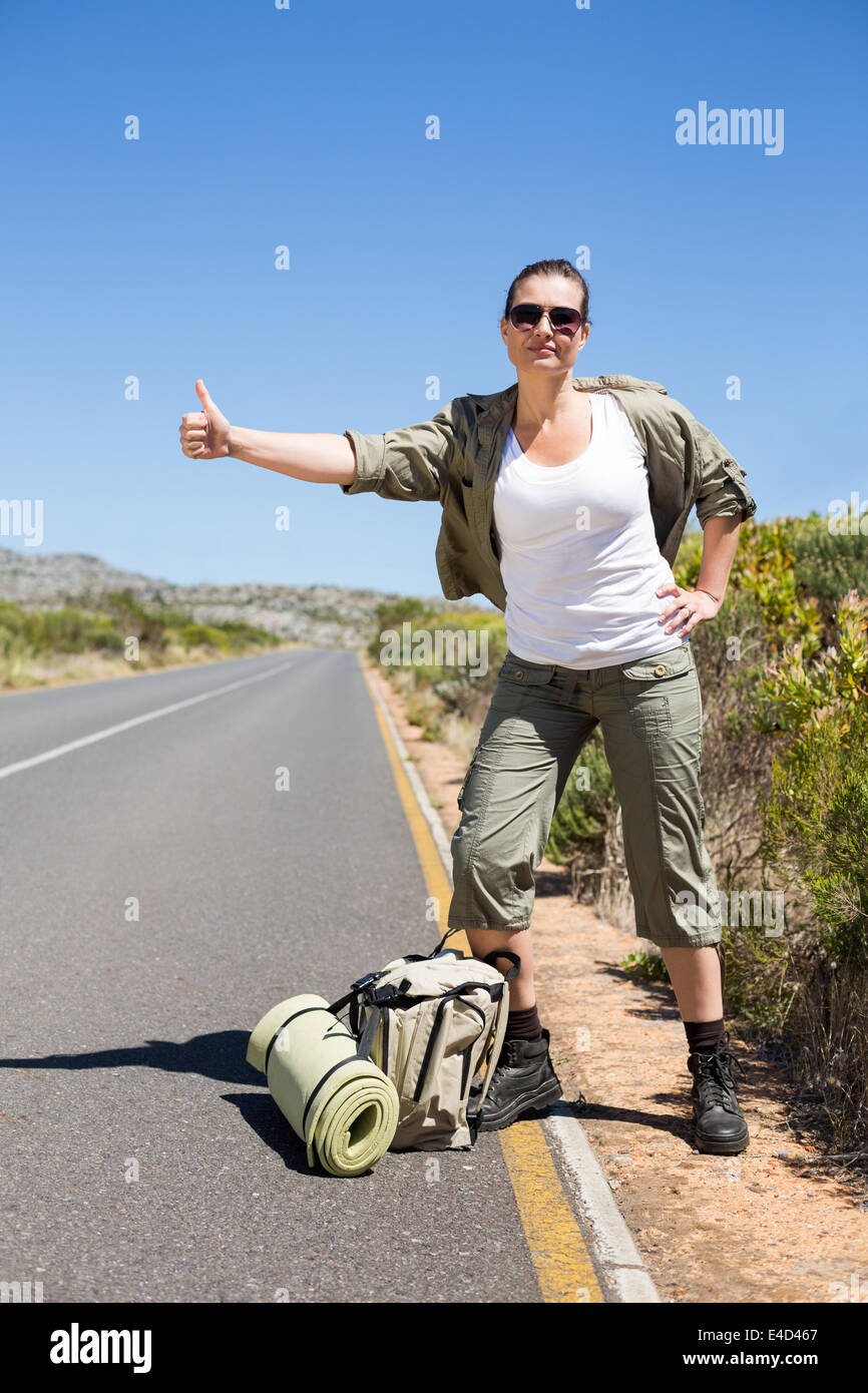 Pretty hitchhiker sticking thumb out on the road Stock Photo