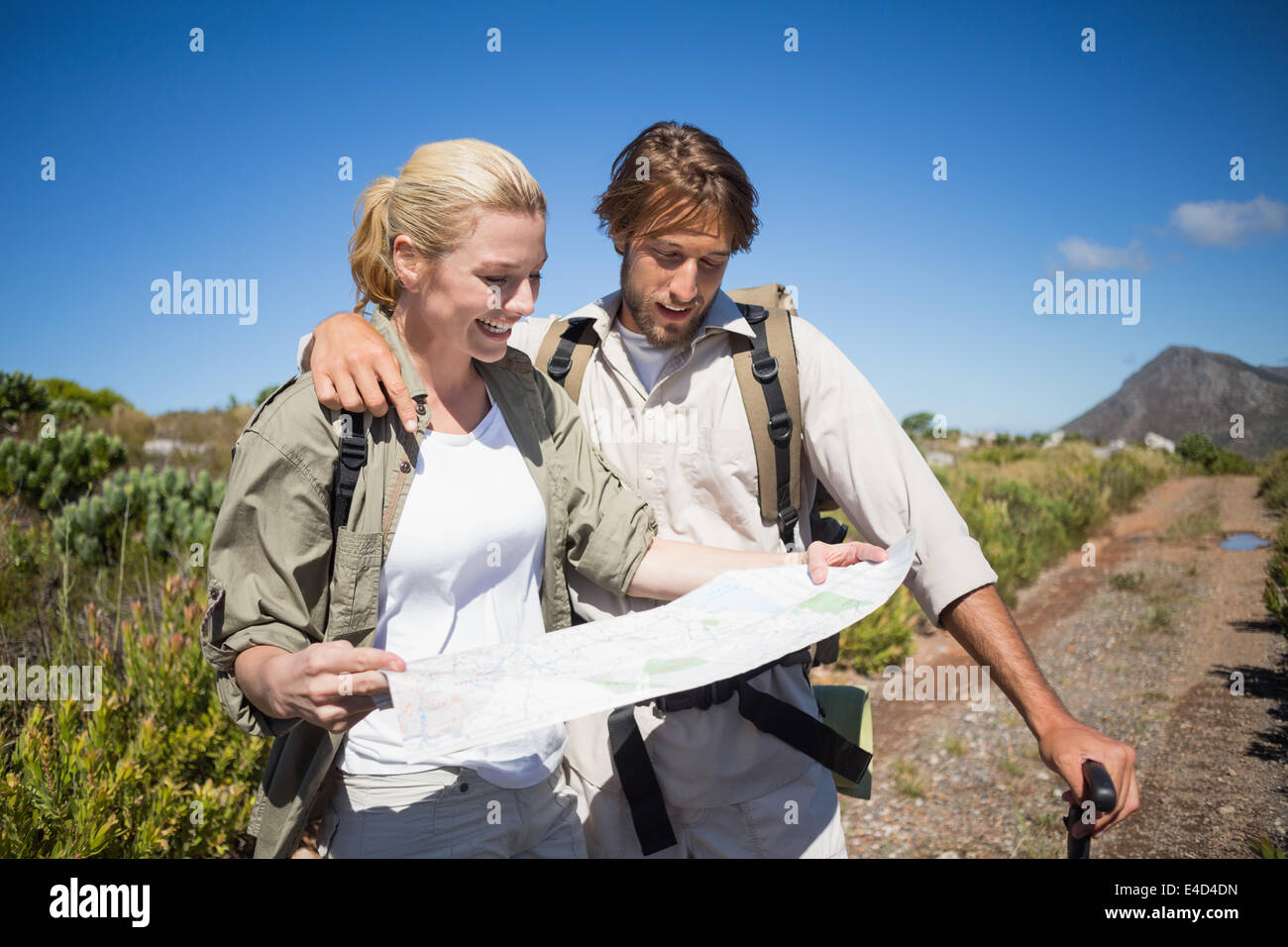 Hiking couple walking on mountain terrain looking at map Stock Photo