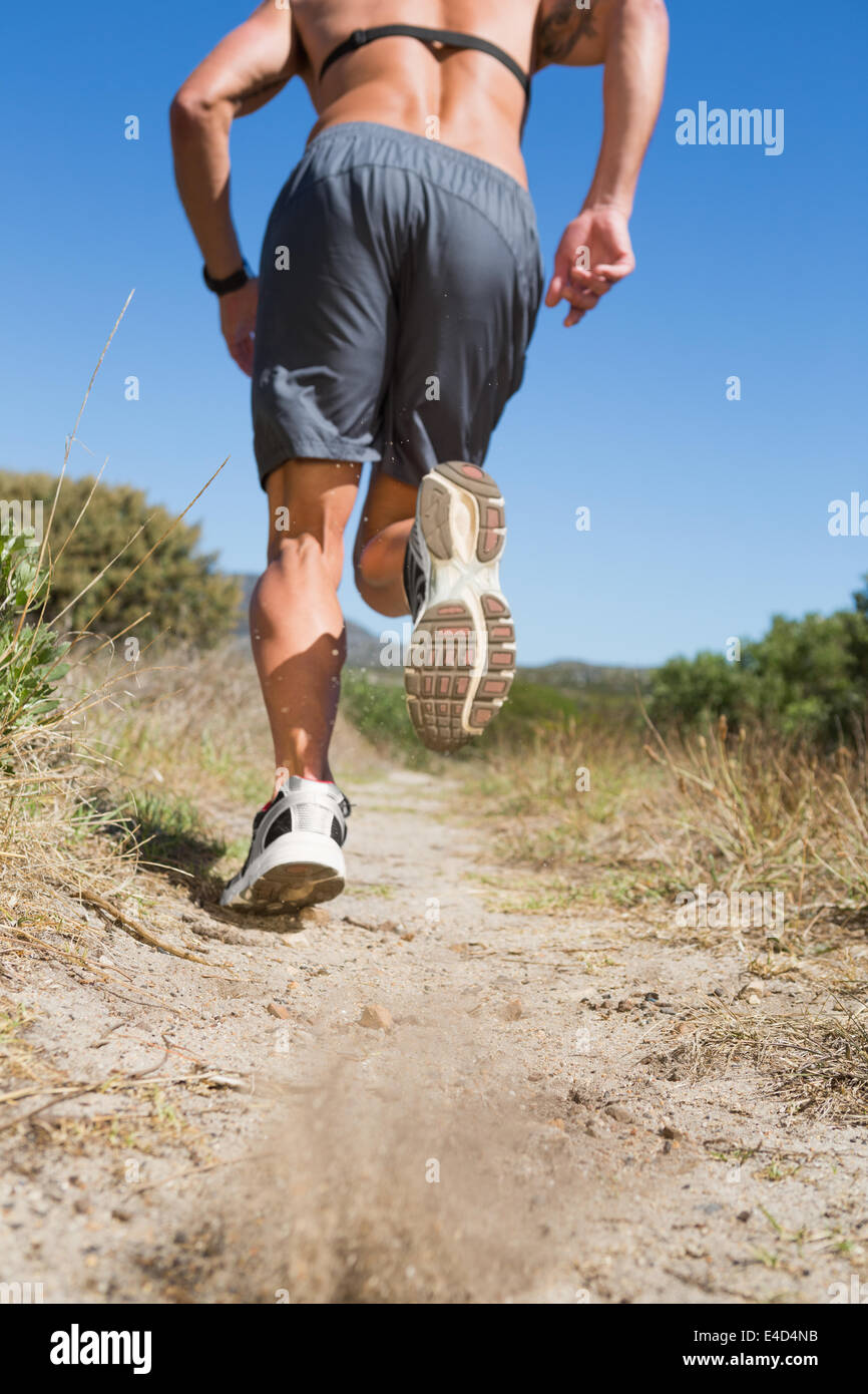 Shirtless man jogging with heart rate monitor around chest Stock Photo