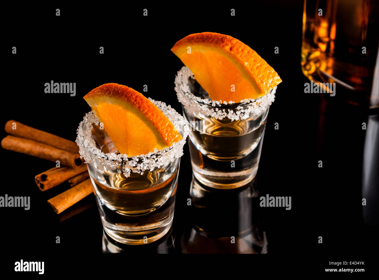 Gold tequila with orange and cinnamon on black reflect background Stock