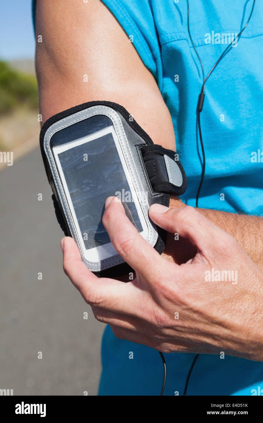 Athletic man adjusting his music player on a run Stock Photo