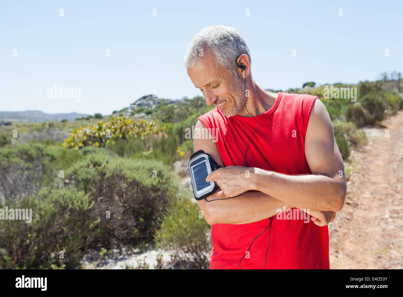 Fit man changing the song on his music player on mountain trail Stock Photo