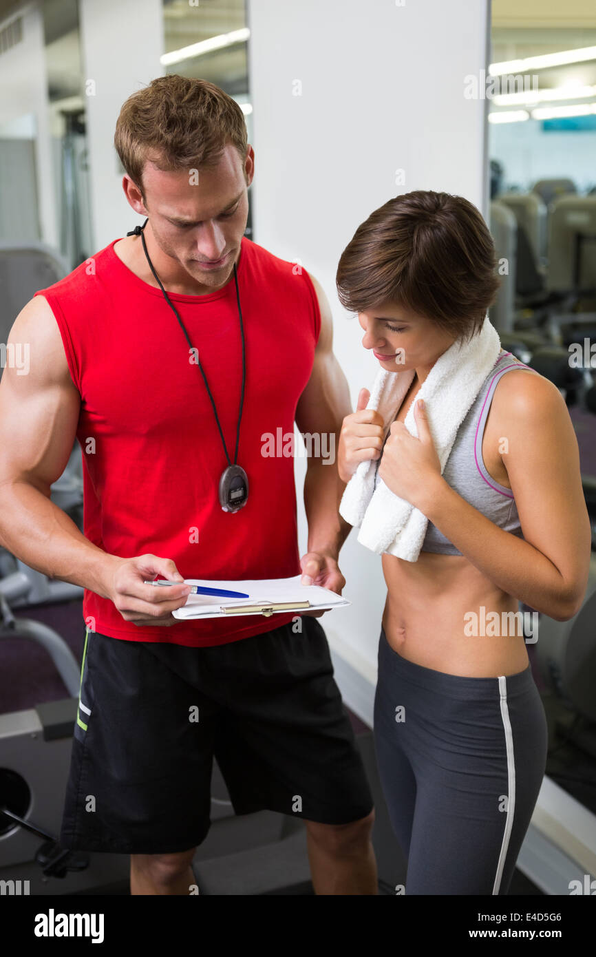 Happy woman smiling on weighing scales at gym. Trainer with female client  checking fitness progress. Personal training programme for weight loss  Stock Photo - Alamy