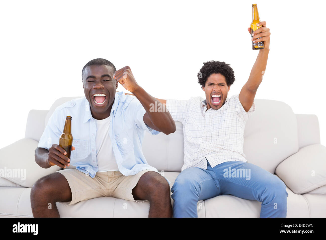 Ecstatic sports fans sitting on the couch with beers Stock Photo