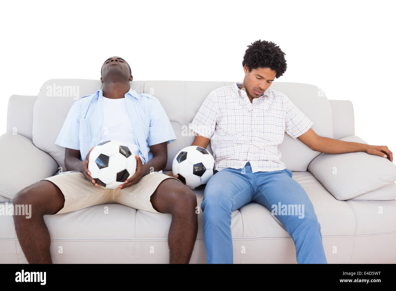 Distraught football fans sitting on the couch with balls Stock Photo