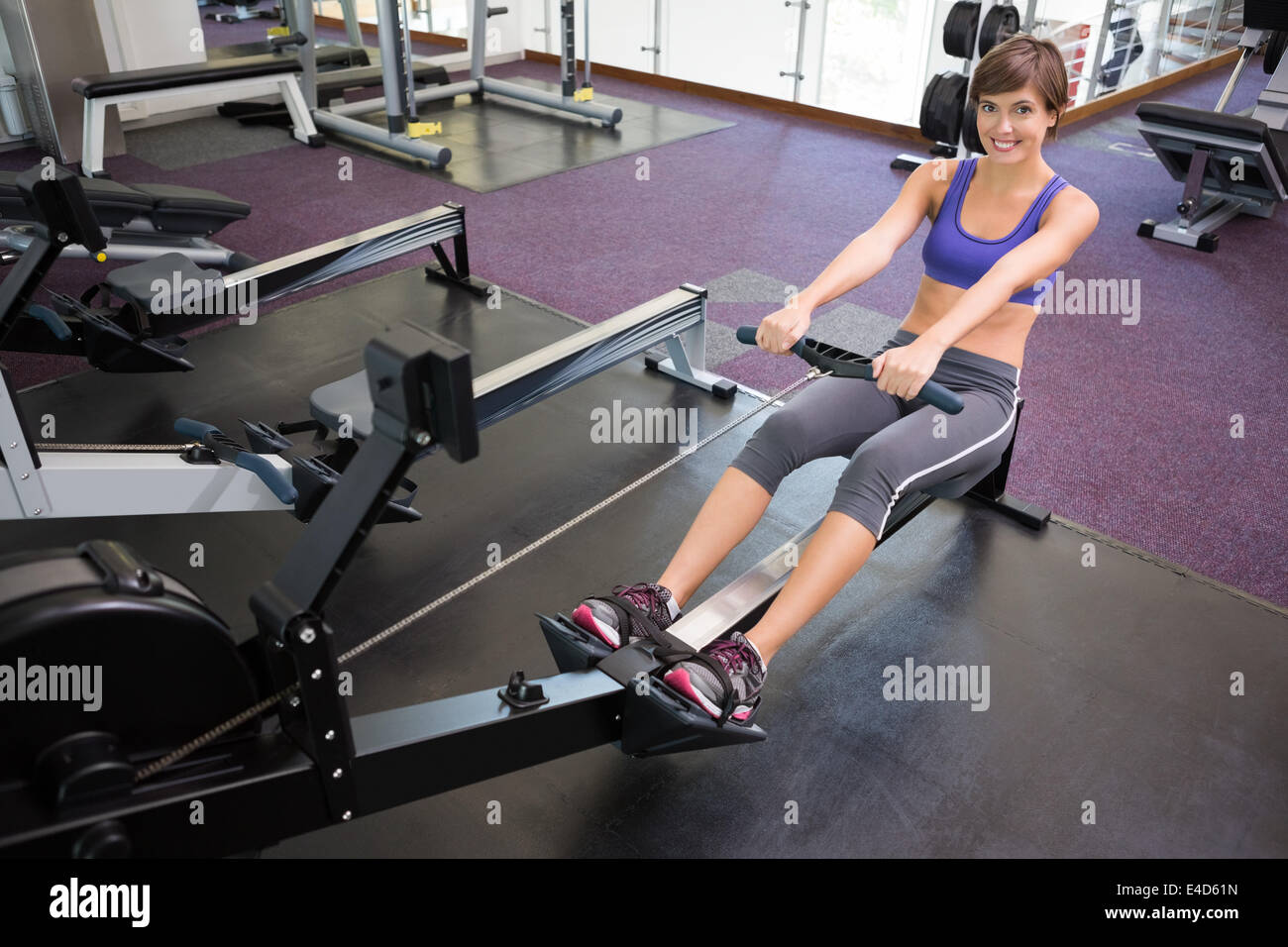 Fit smiling brunette working out on rowing machine Stock Photo - Alamy