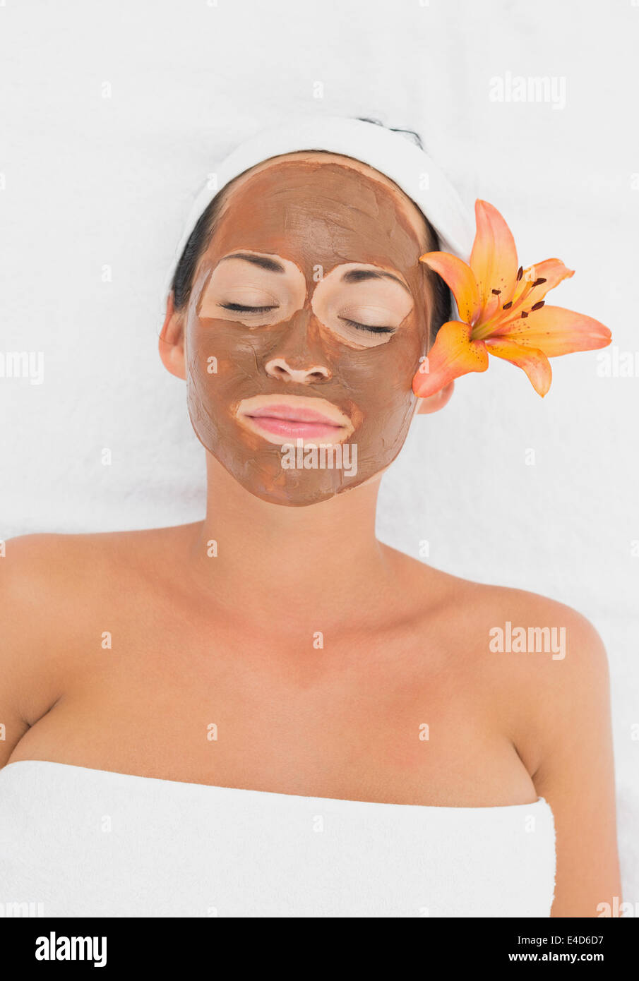 Smiling brunette getting a mud treatment facial Stock Photo