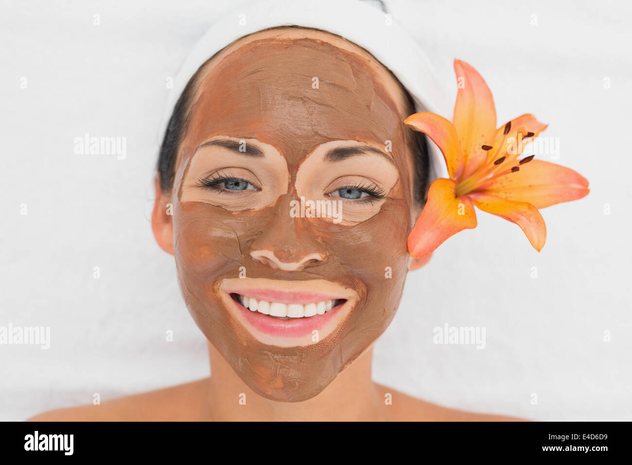 Smiling brunette getting a mud treatment facial Stock Photo