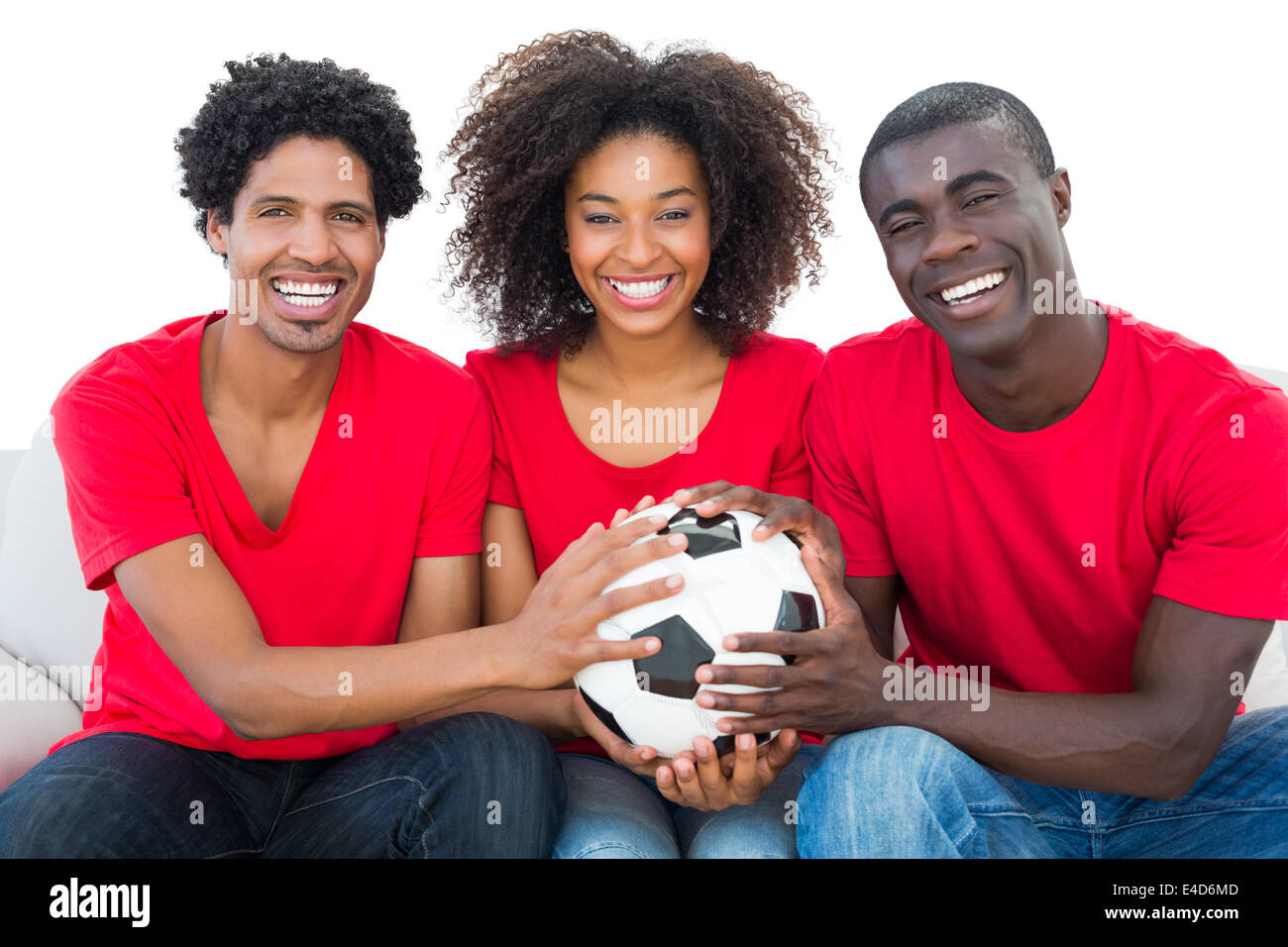 Happy football fans in red holding ball together Stock Photo