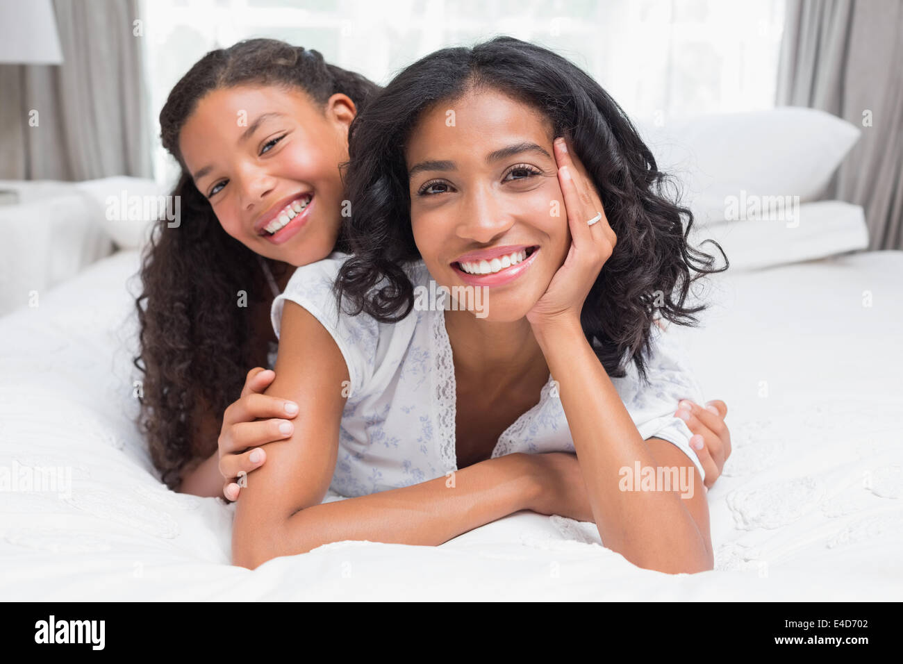 Pretty woman lying on bed with her daughter smiling at camera Stock ...