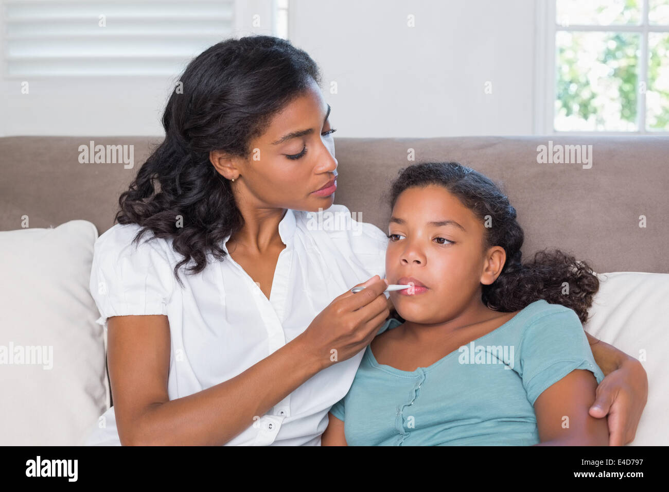Concerned mother taking her daughters temperature Stock Photo