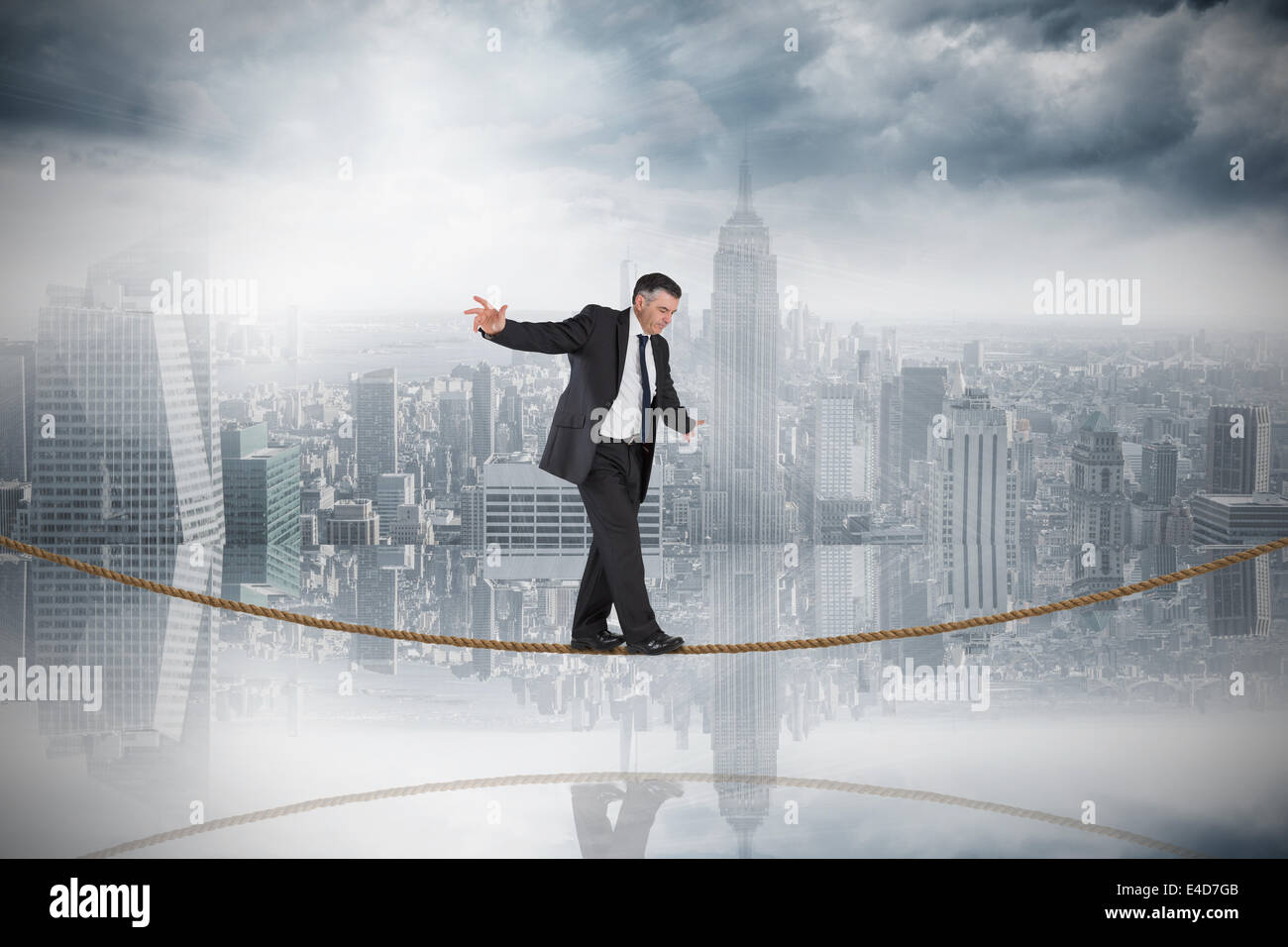 Composite image of mature businessman doing a balancing act on tightrope Stock Photo