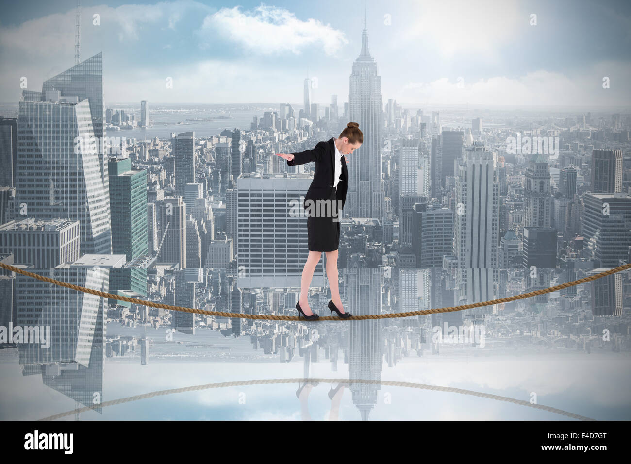 Composite image of businesswoman performing a balancing act on tightrope Stock Photo