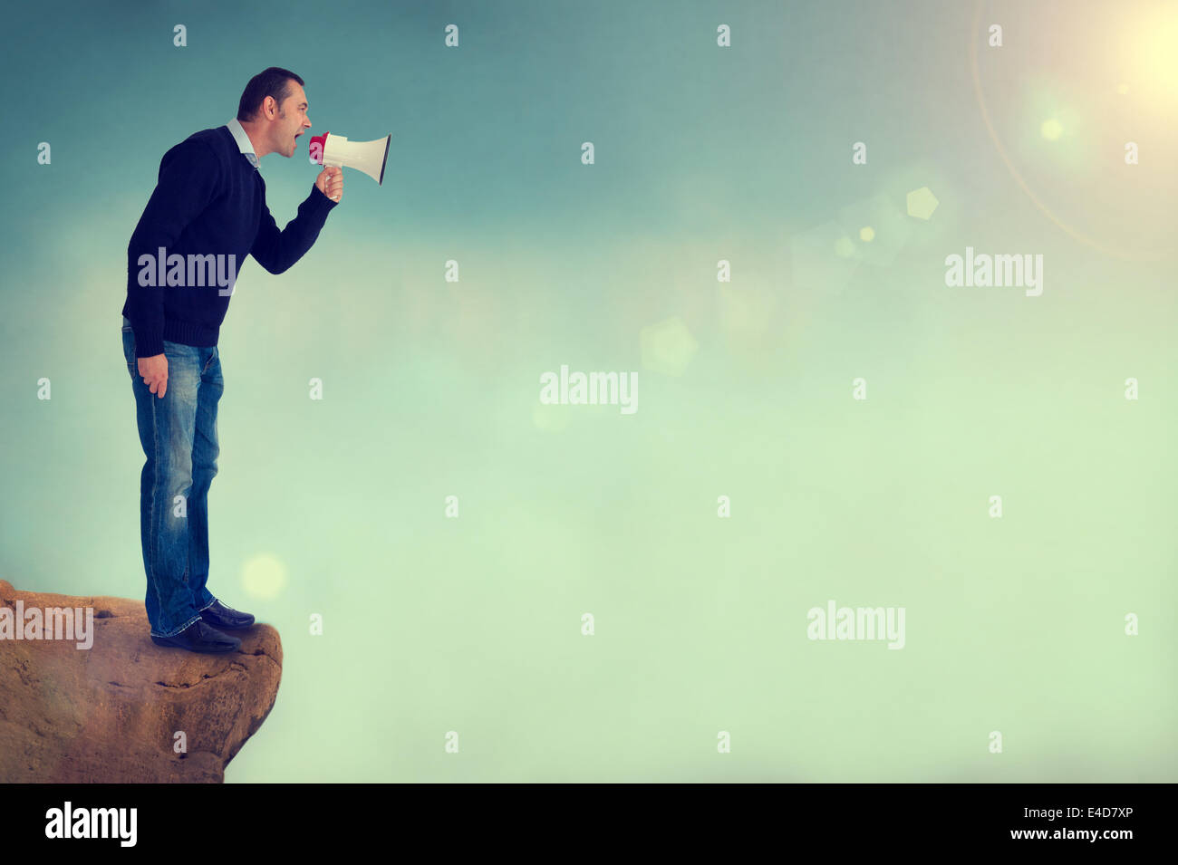 man with a bullhorn, loudhailer or megaphone shouting from edge of a cliff Stock Photo