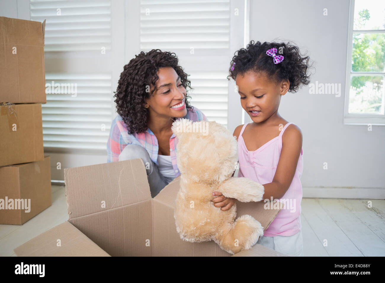 Cute daughter unpacking her teddy bear with mother Stock Photo