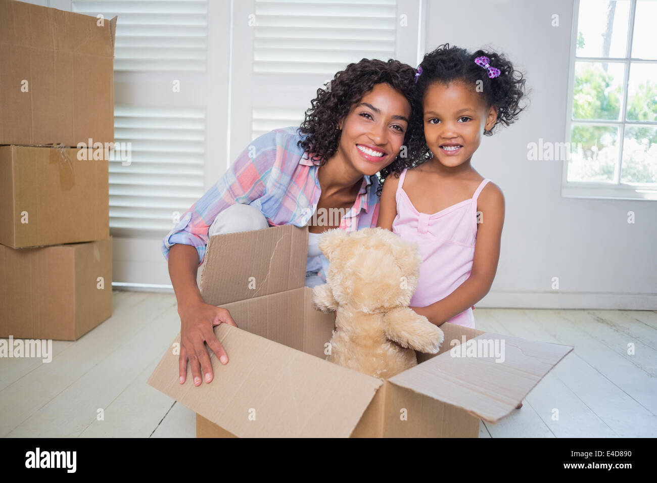 Cute daughter unpacking her teddy bear with mother Stock Photo
