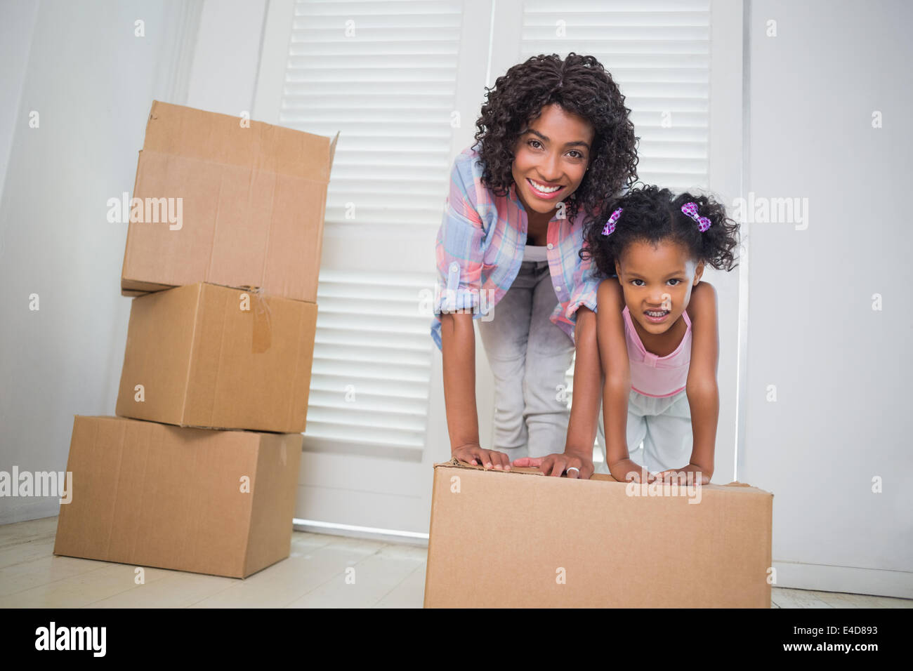 Cute daughter unpacking moving boxes with her mother Stock Photo
