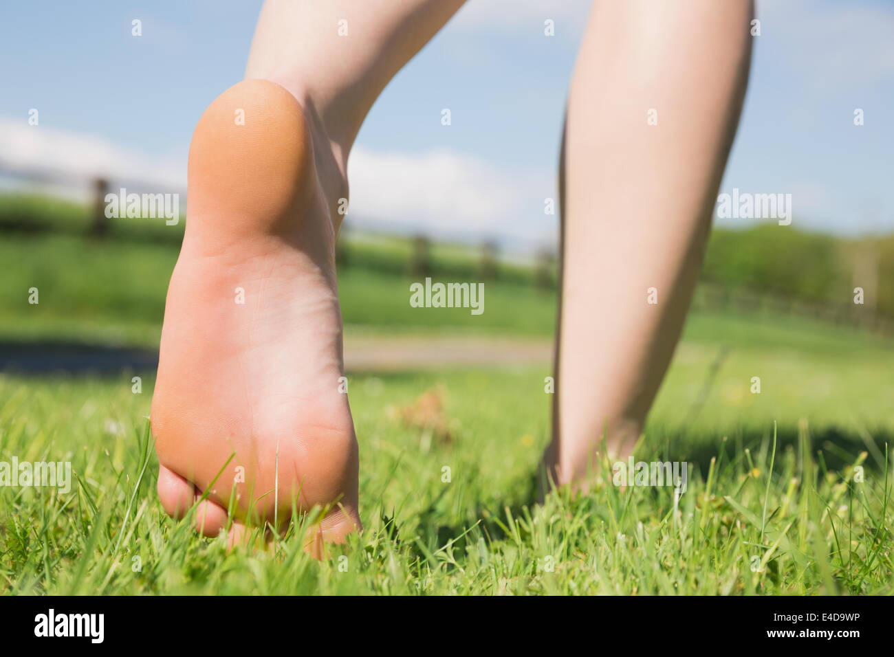 Womans feet walking away on grass Stock Photo