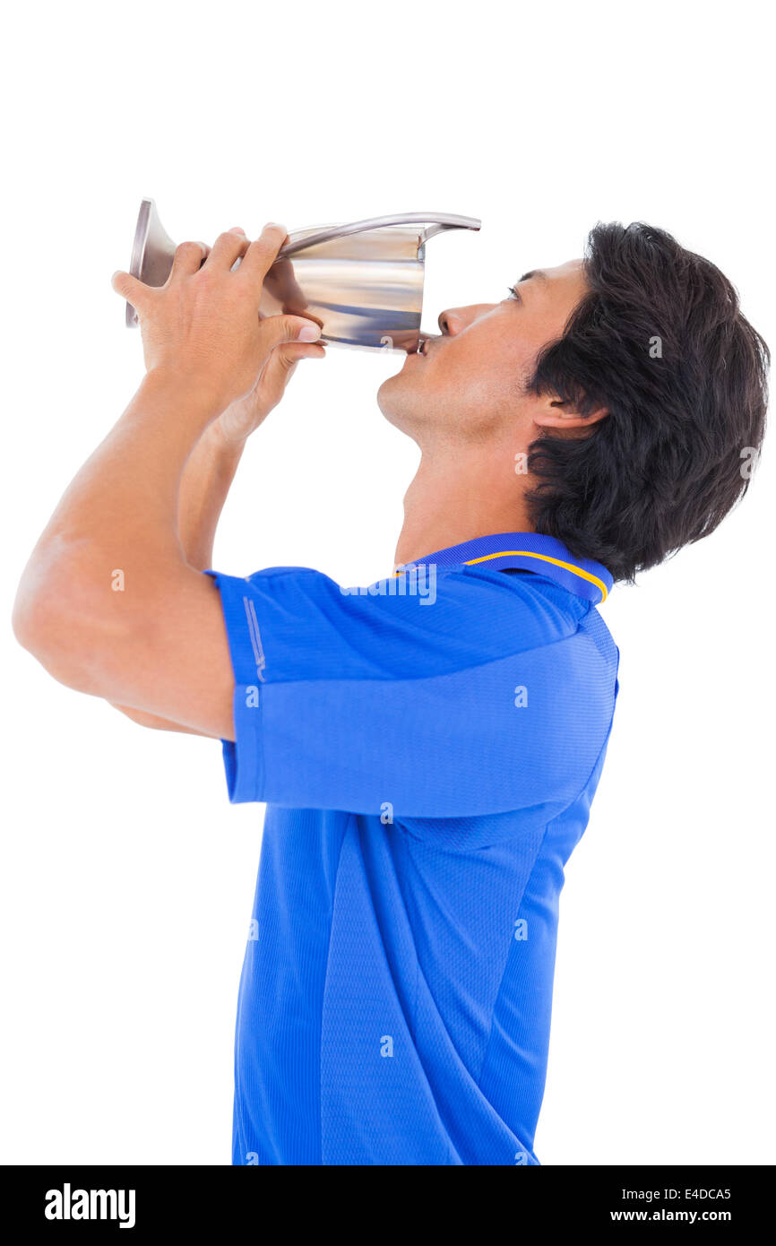 Football player in blue kissing winners cup Stock Photo