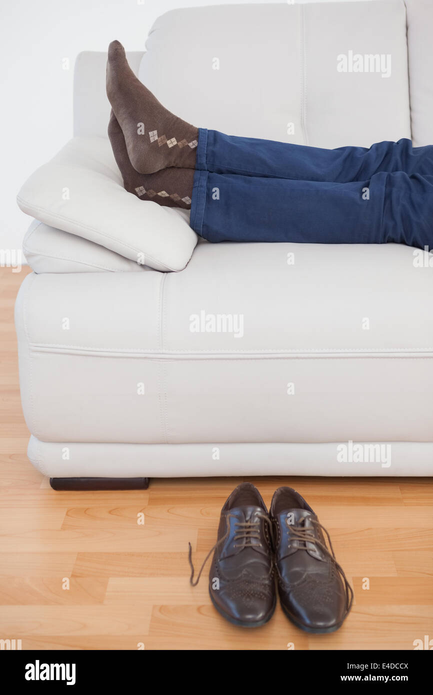 Tired businessman lying on sofa with shoes off Stock Photo