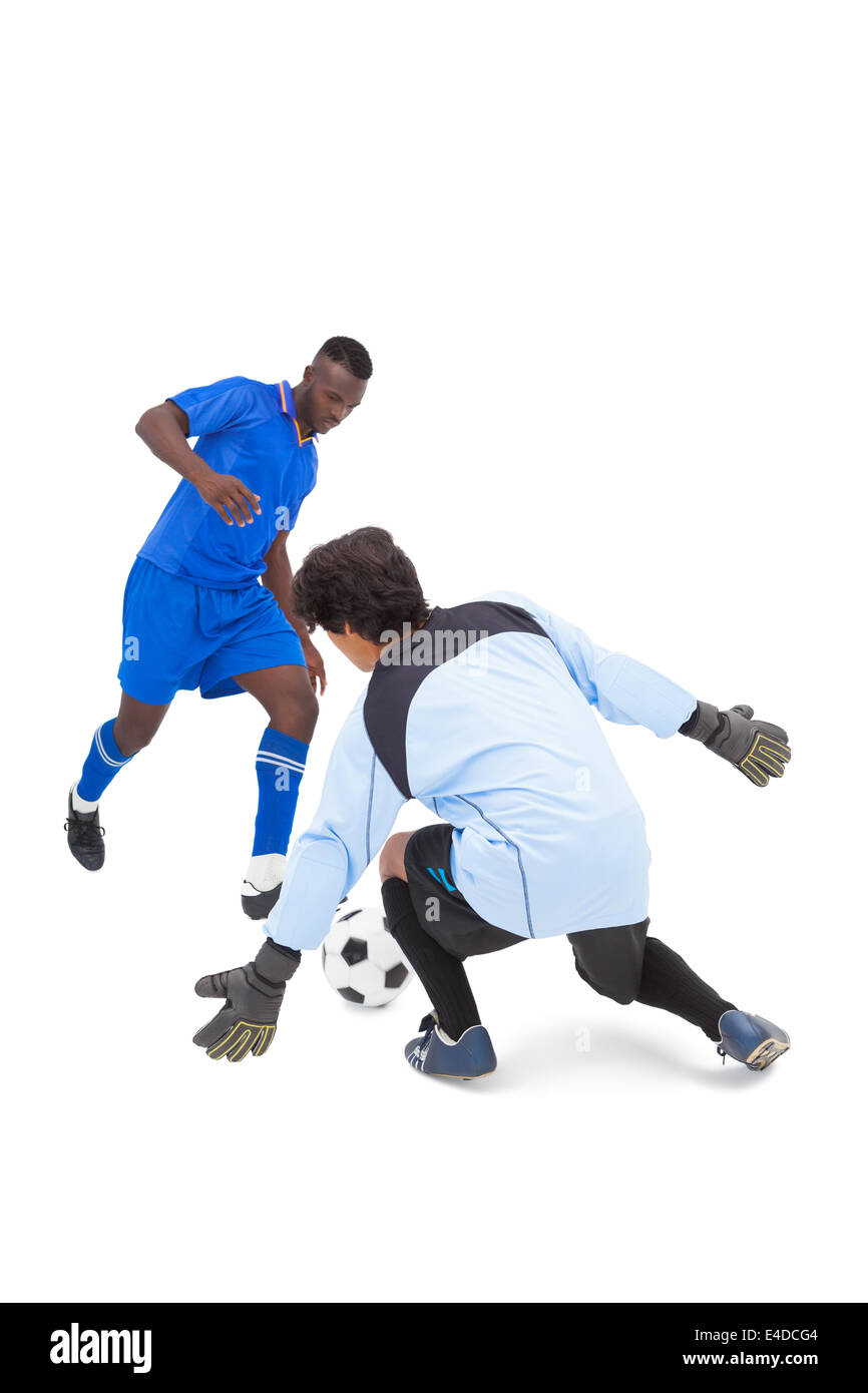Football player in blue striking at keeper Stock Photo